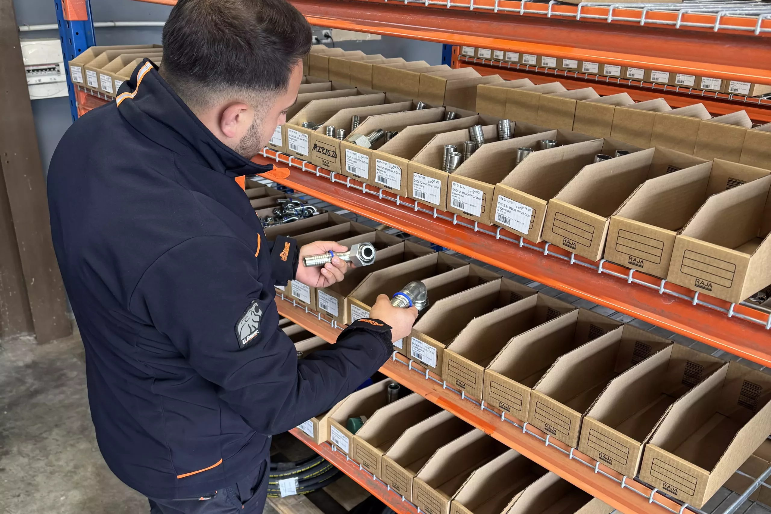 Technicien Full Service Industrie devant le rayonnage des raccords hydrauliques du comptoir d’Ablon-sur-Seine