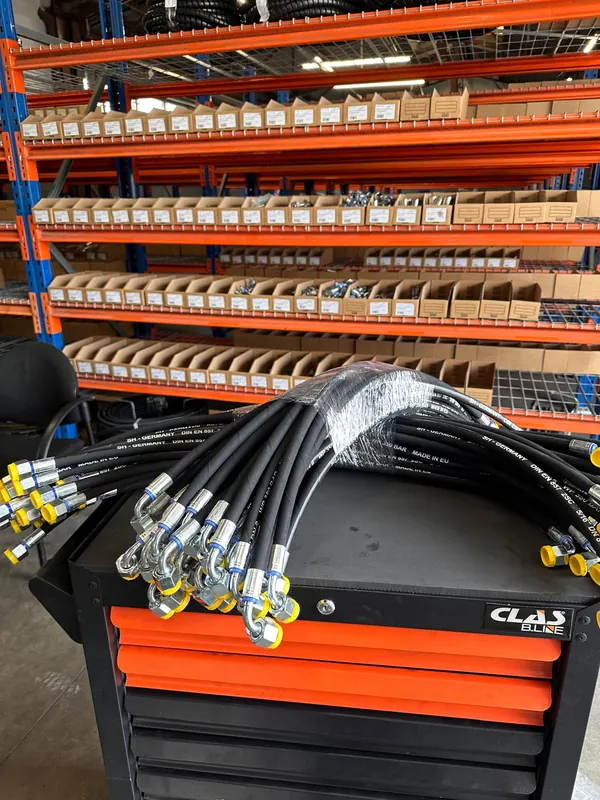 Flexibles hydrauliques neufs devant le rayonnage des raccords